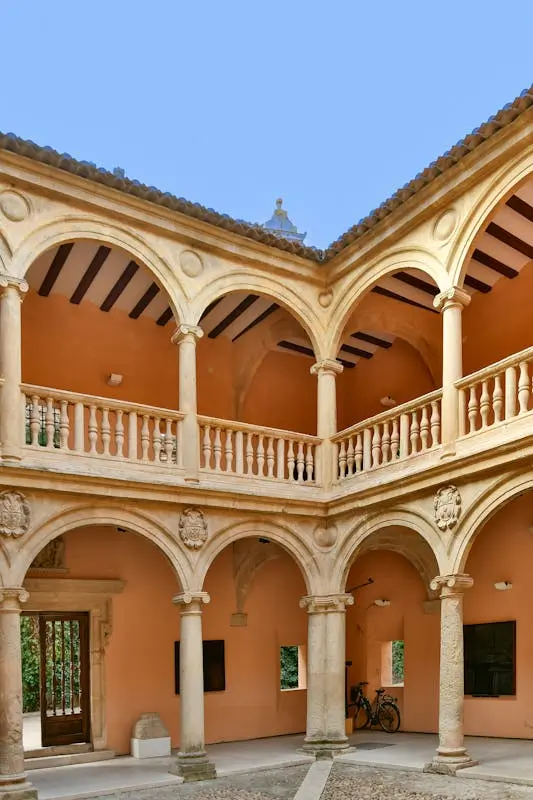 Elegant courtyard with arches and columns in Almansa, Spain under a clear sky.