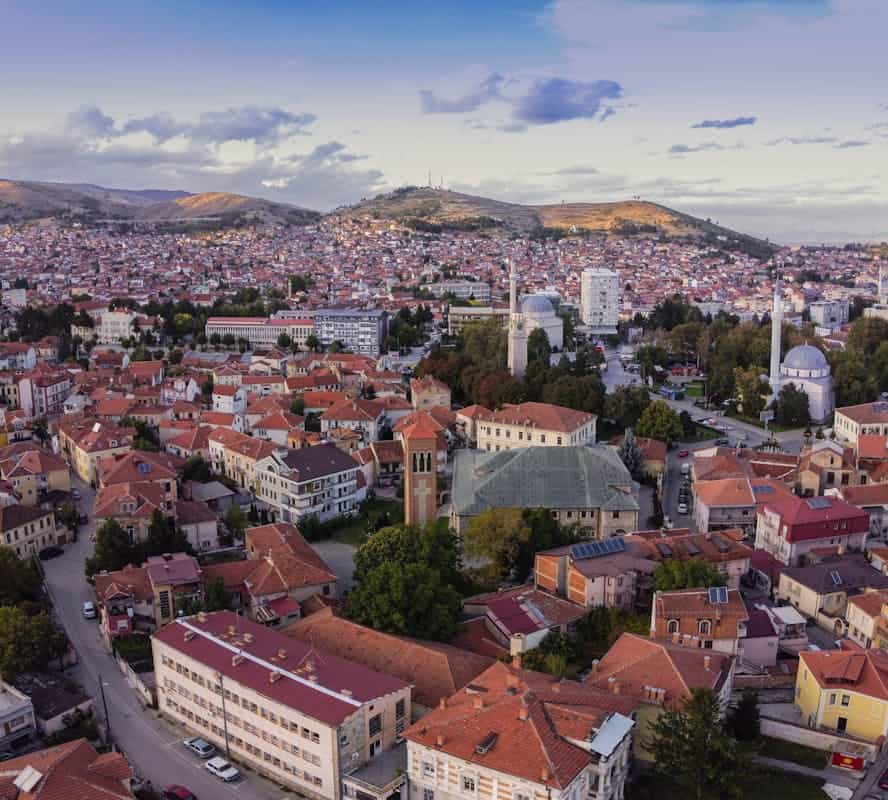 Aerial image showcasing the picturesque townscape of Bitola, North Macedonia, featuring red-roofed buildings and scenic hills of Bitols