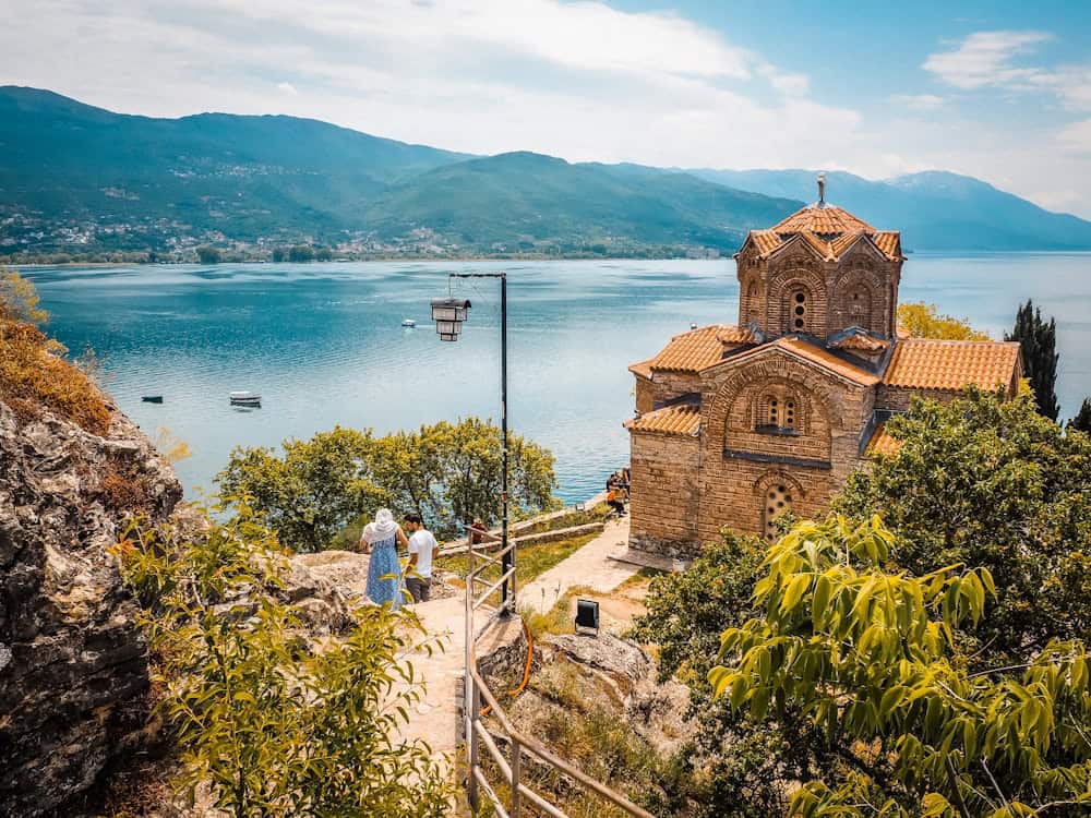 a group of people walking up a hill next to a body of water at Lake Ohrid, Morth Macedonia