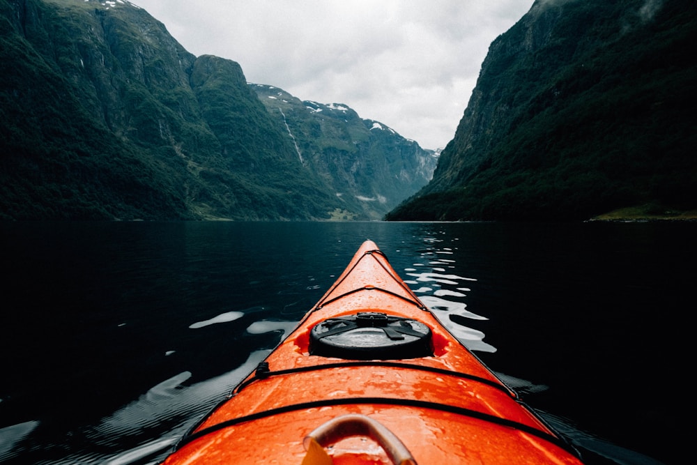orange canoe on Norway fjords surrounding with mountain at daytime