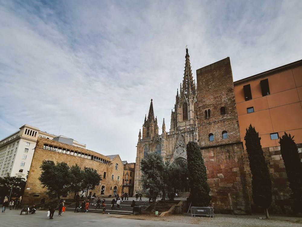 View of a gothic cathedral in Barcelona, surrounded by urban architecture.