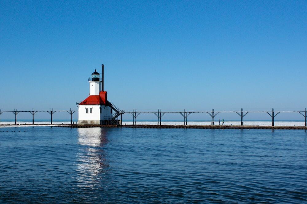 white and red lighthouse on dock on Lake Michigan