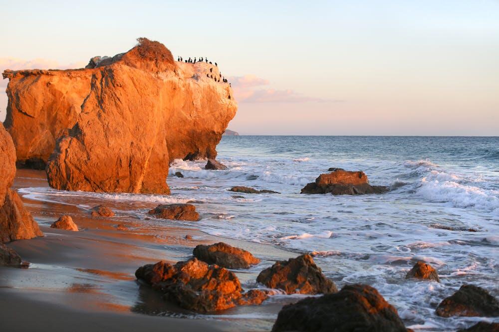 Scenic view of rocky shoreline with birds during sunset, on El Matador Beach, California